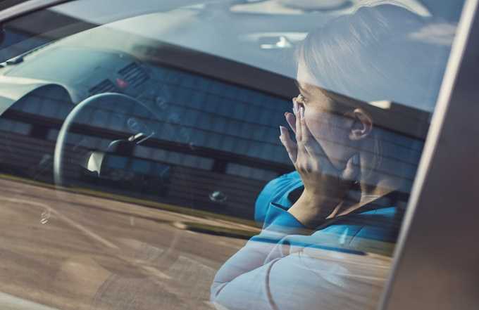 Erschrockene Frau im Auto als Symbolbild für Betrug beim Autokauf