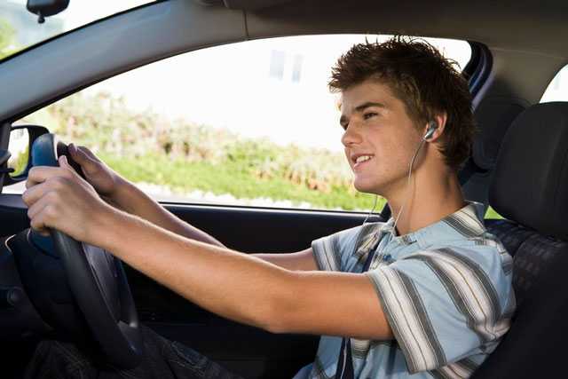 Junger Autofahrer beim Telefonieren mit Kopfhörern