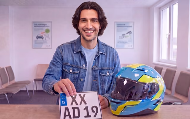 Mann hält das Kennzeichen seines Motorrads