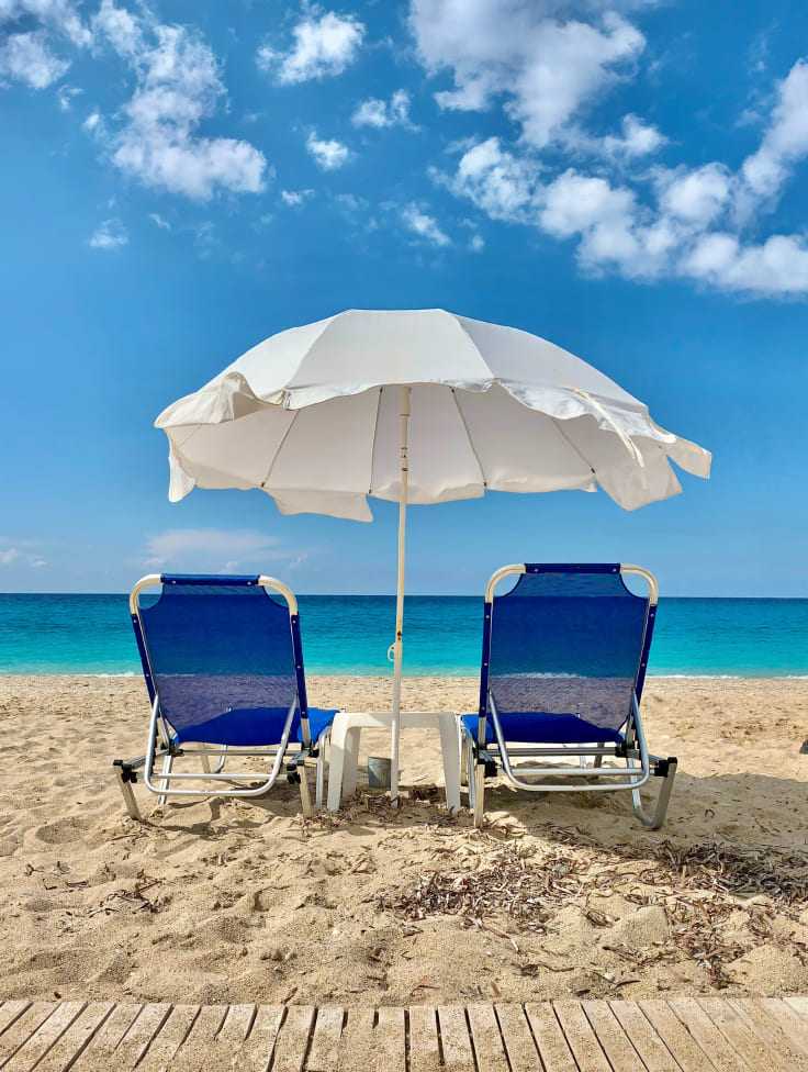 Liegestühle mit Sonnenschirm am Strand 