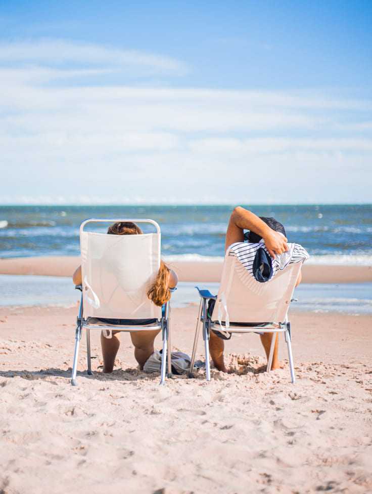 Zwei Personen auf Liegestühlen am Strand