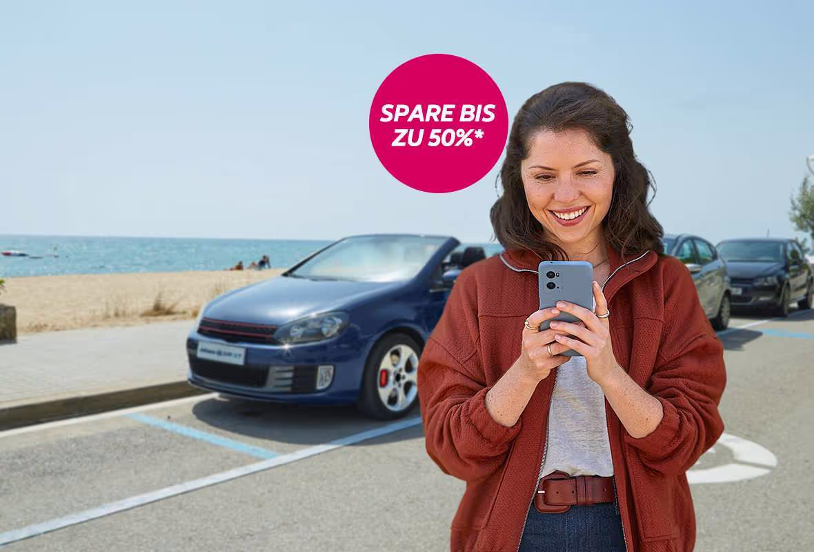 Frau mit Handy vor Auto